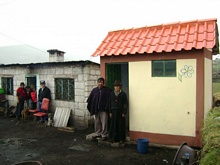Una familia beneficiaria delante del baño terminado