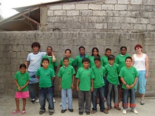 Our children using their shirts from the guagua program next to Carlo and Barbara